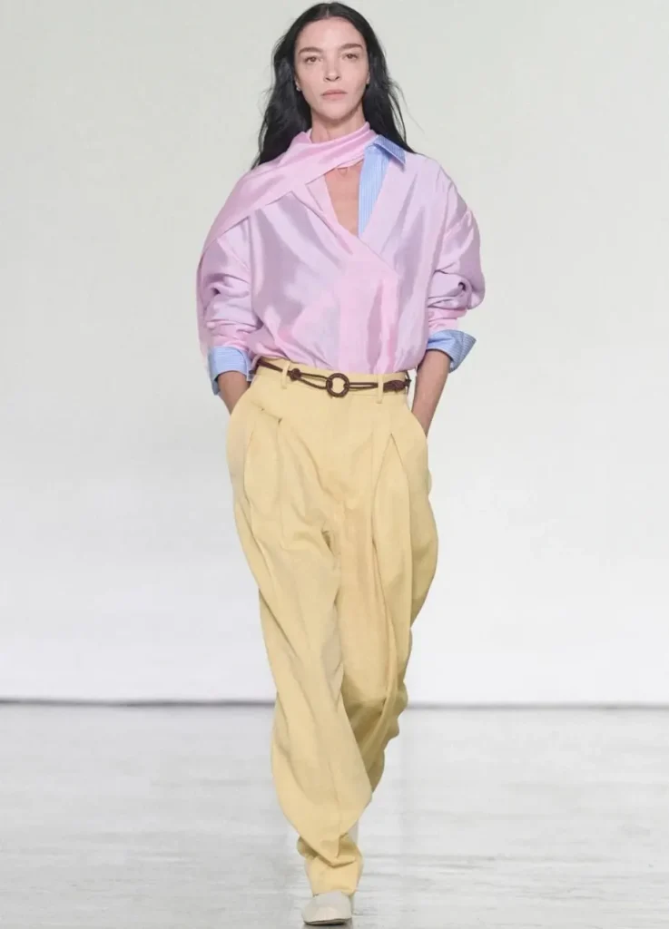 Bottega Veneta Spring 2027 Look 17,
pink satin draped top over blue striped shirt with butter yellow pleated trousers